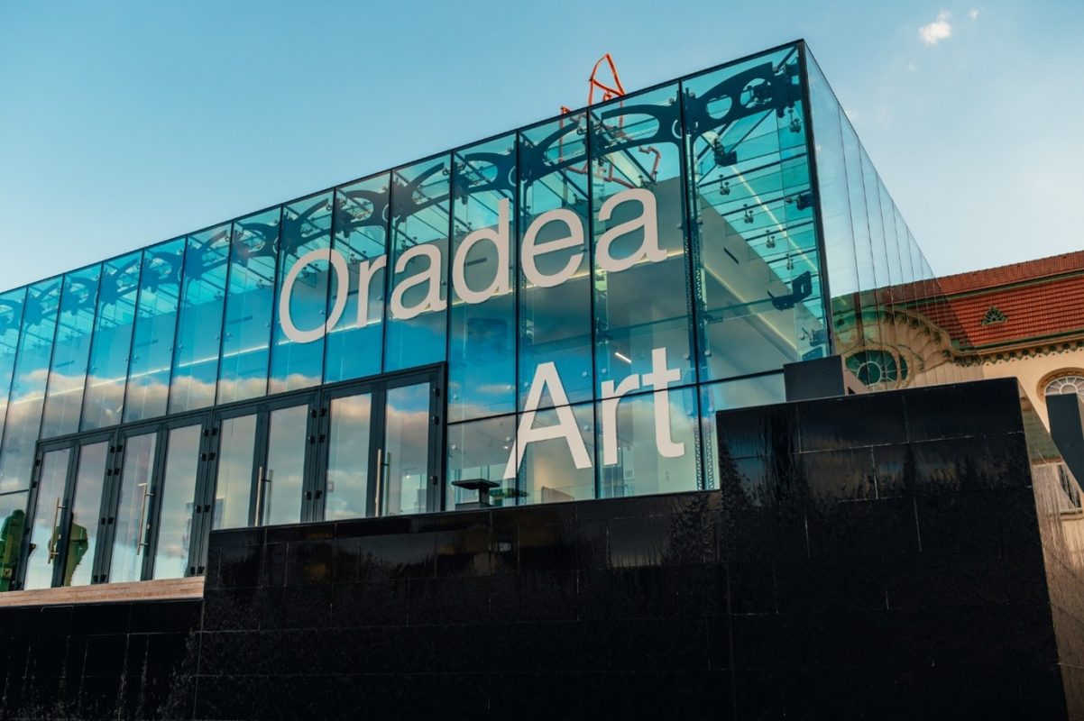 Oradea Art Museum's modern glass facade with the museum's name displayed.